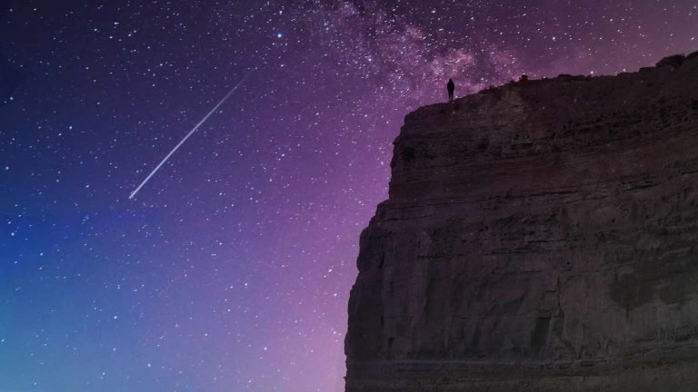 A person standing on a cliff watching a blazing star