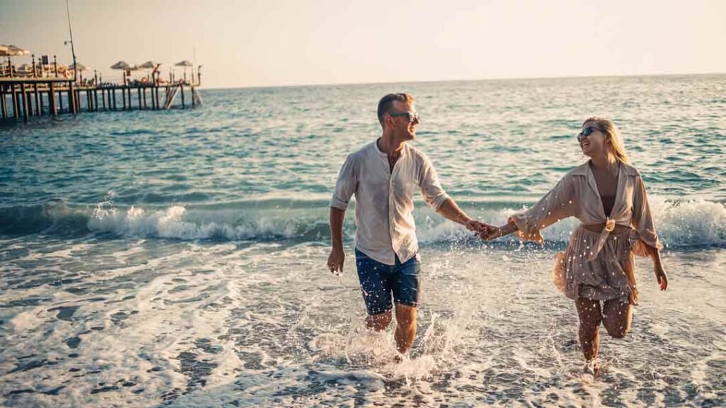 a dating couple holding hands on the beach