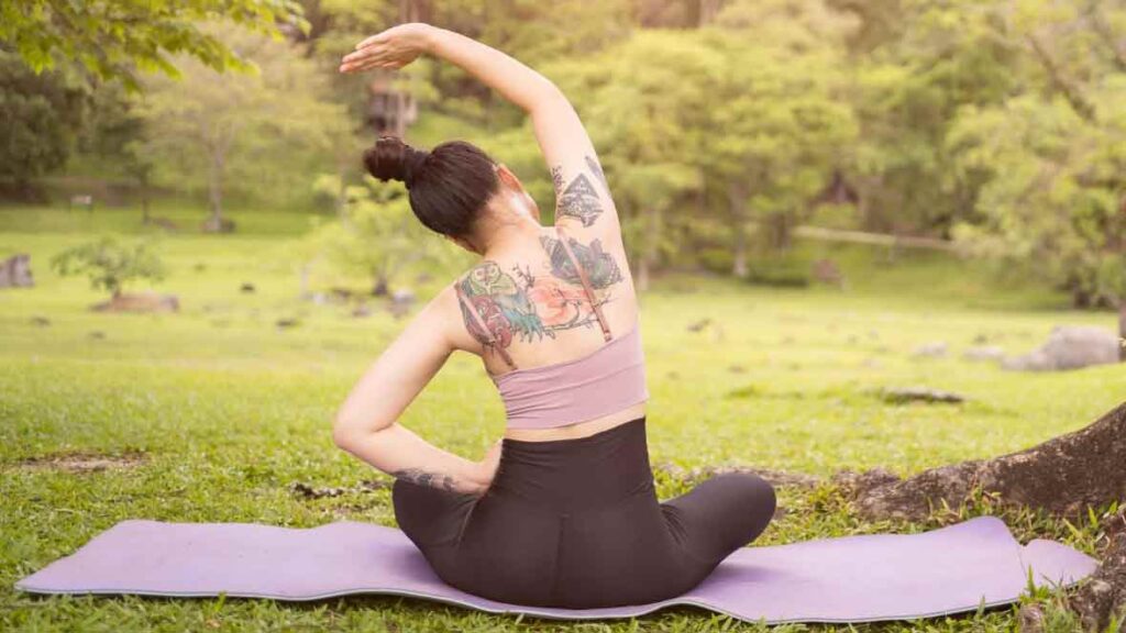 a woman with tattoos on her back doing yoga