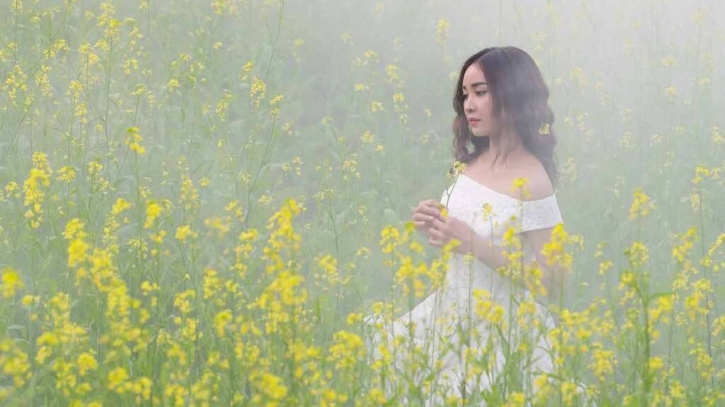 a beautiful woman walking in a field of flowers