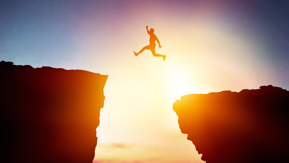 brave man jumping across a cliff