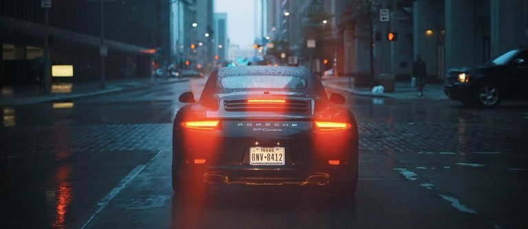 a black Porsche driving in a city
