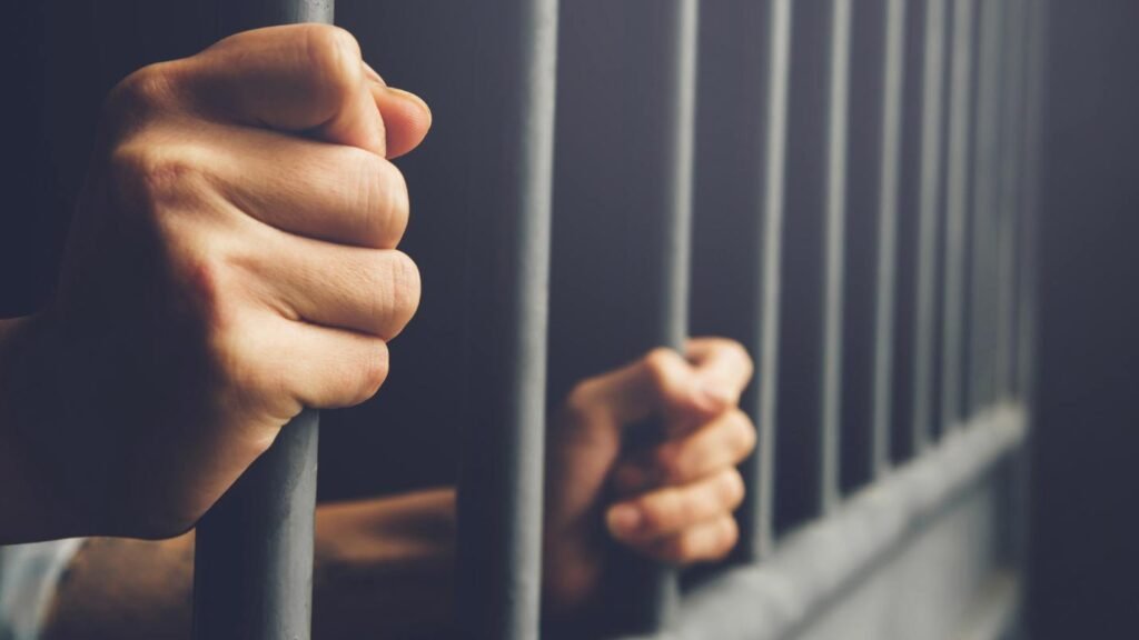 hands on the bars of a jail cell