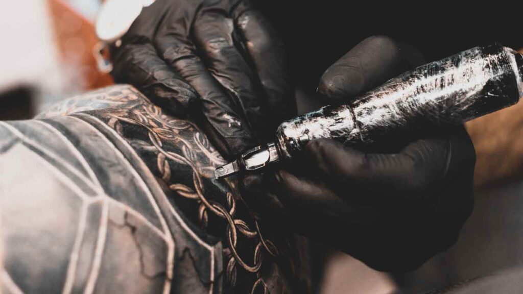 A tattoo artist working on an arm