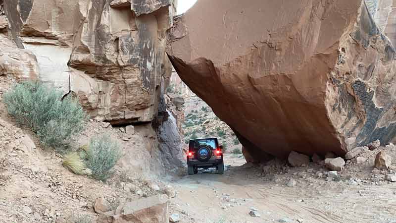 a car driving under a fallen boulder