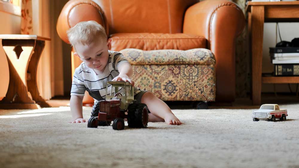 child playing with toy cars on carpet
