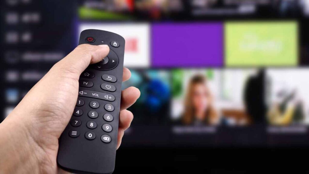 a hand pressing a remote control