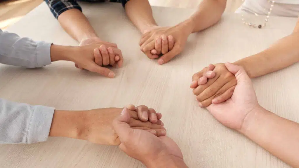 four people holding hands on a table