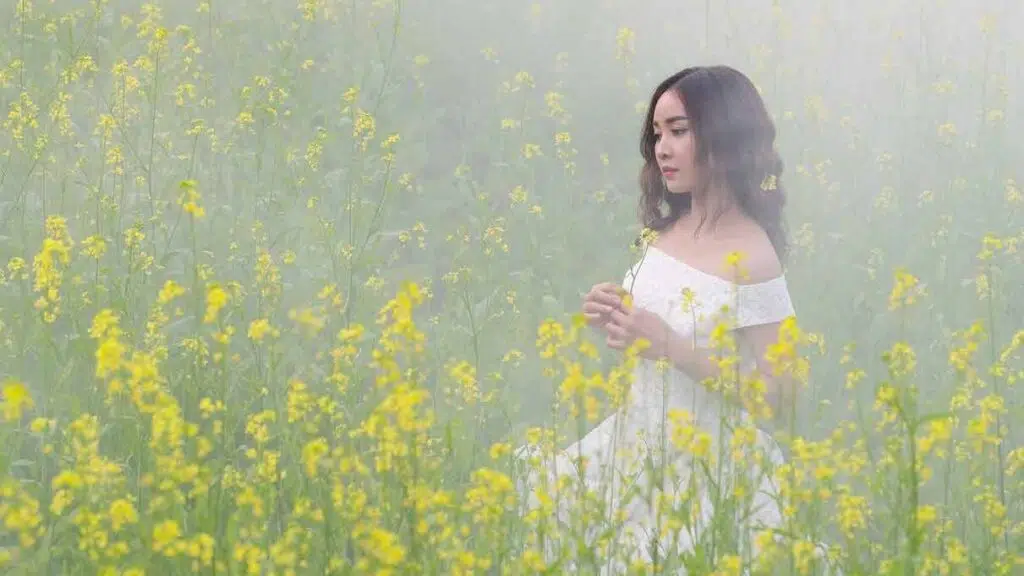 a beautiful woman walking in a field of flowers