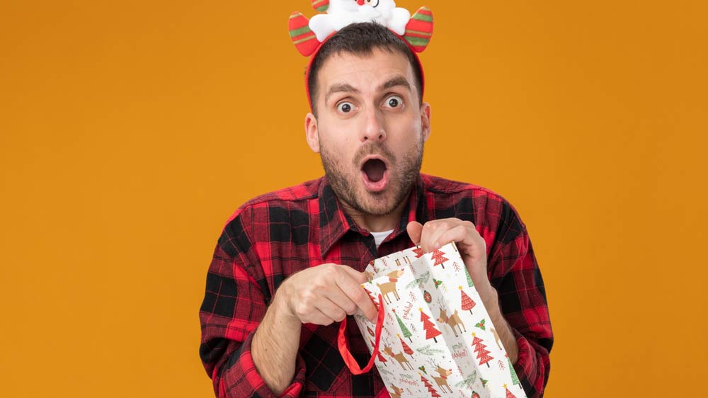 a surprised man with a Christmas gift